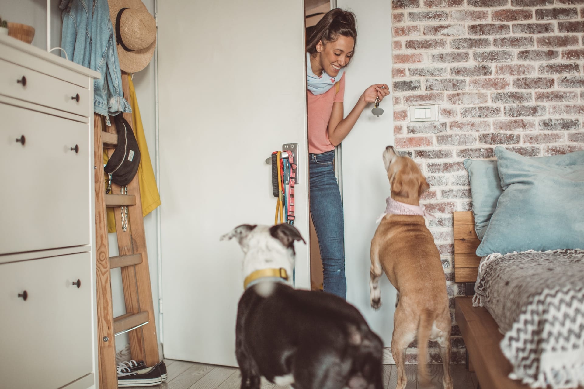 A women at the door with two dogs jumping towards her