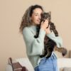 A woman holding a tabby cat in a cozy indoor setting.