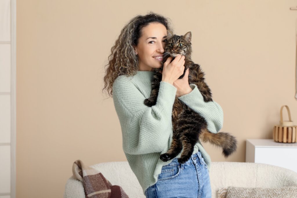 A woman holding a tabby cat in a cozy indoor setting.
